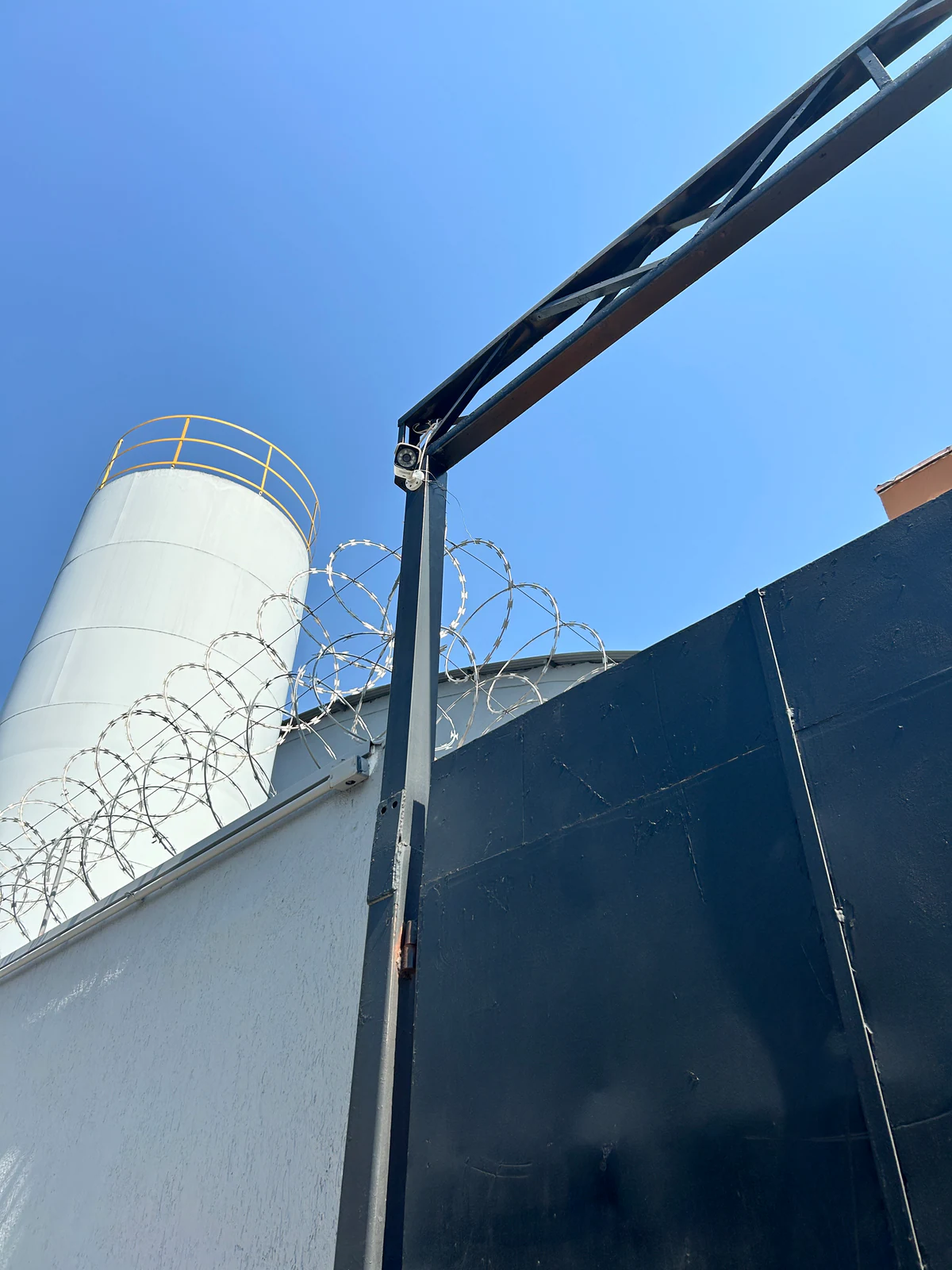Câmera instalada em suporte metálico na área externa de um imóvel.
